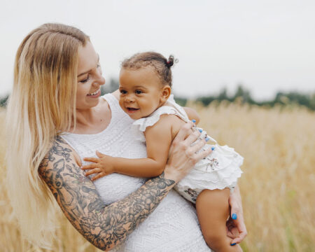 mom with tattoos in an open field with her baby