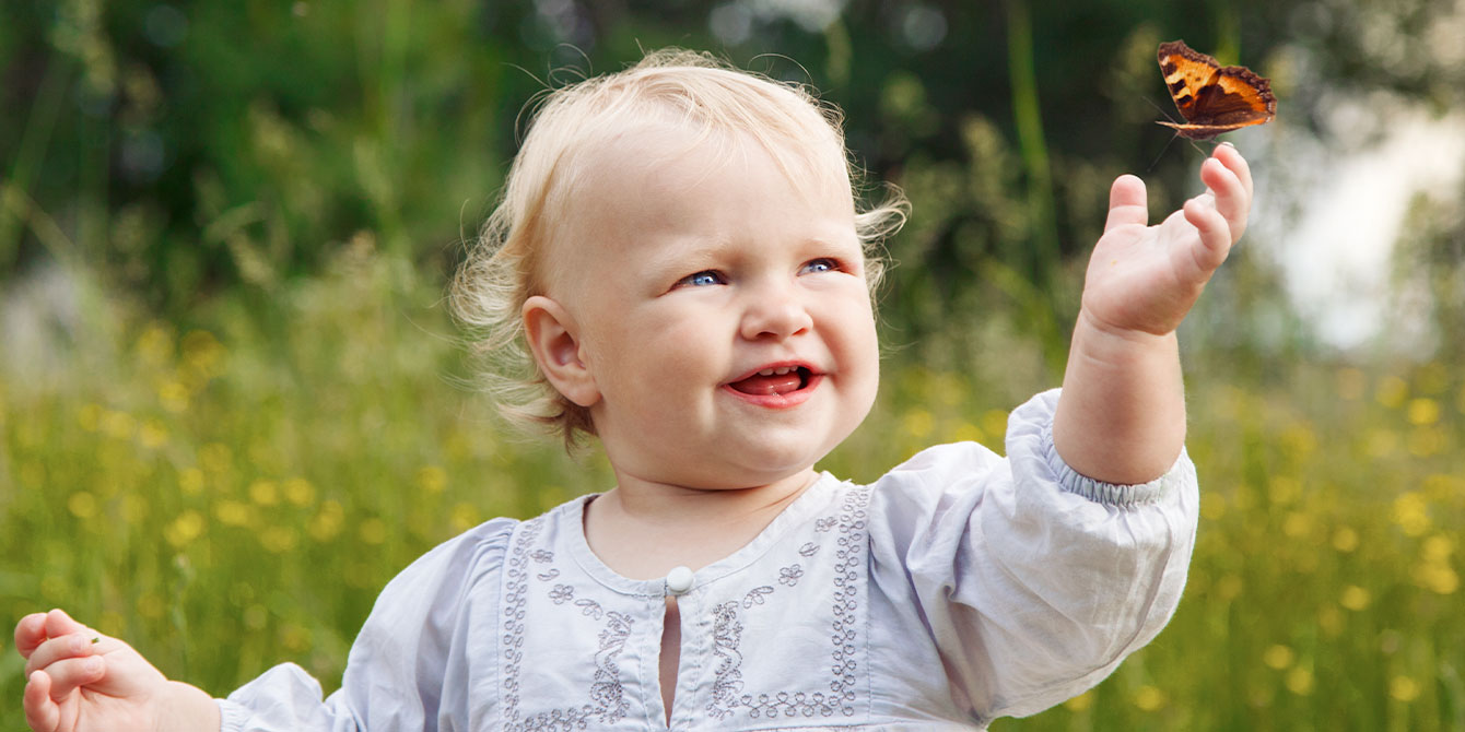 toddler outside with butterfly on her hand- birth month butterflies