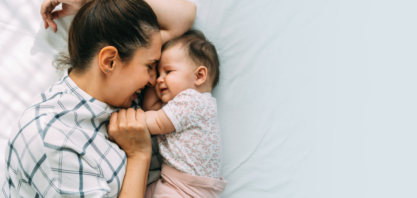 mom and baby snuggling on a bed - introducing the new Motherly