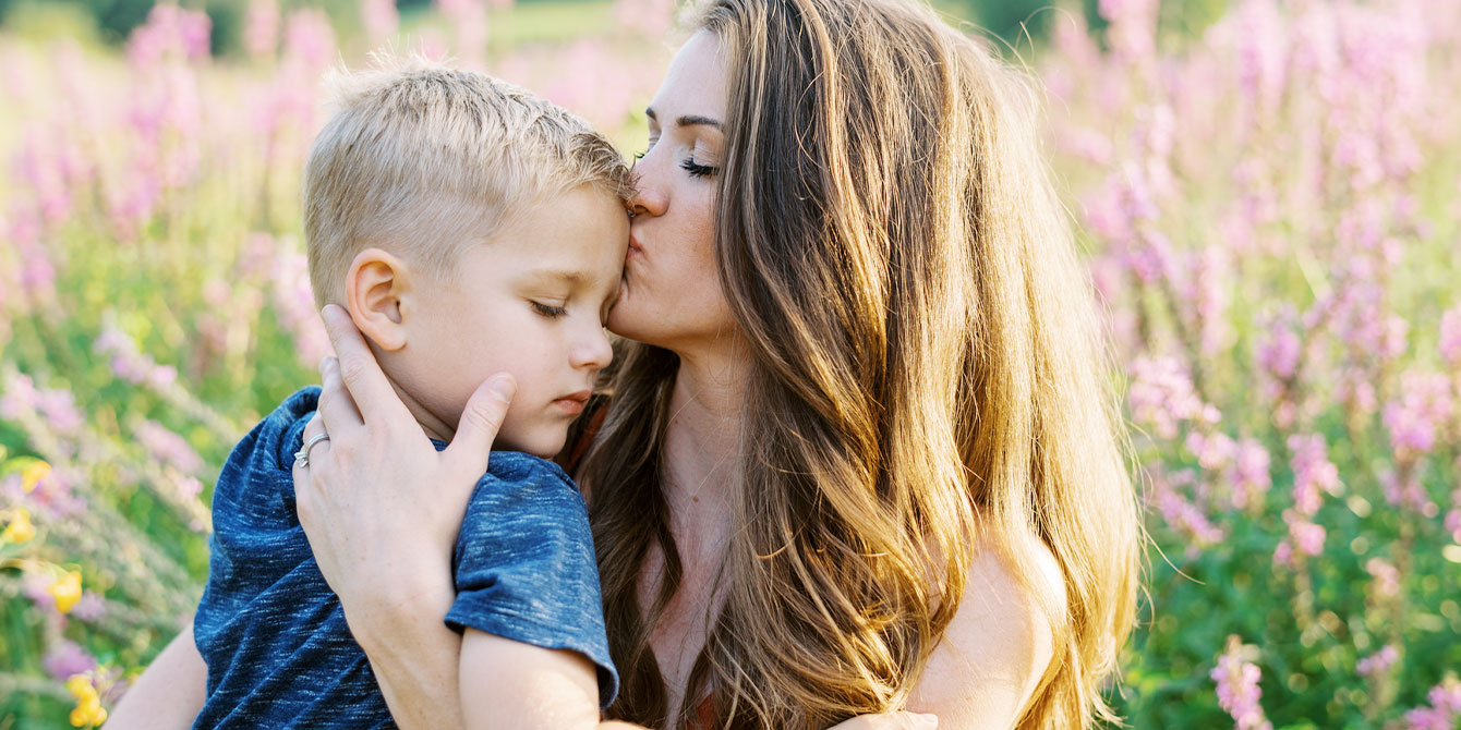 mother kissing son in field of flowers
