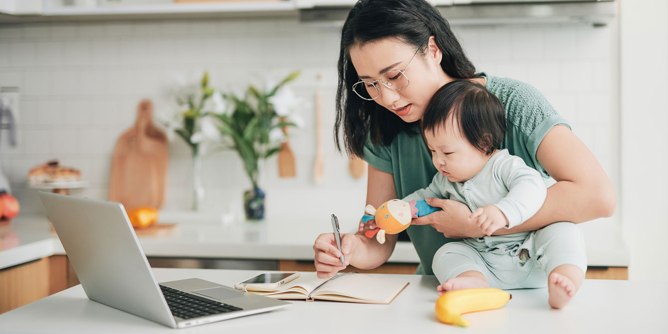 mom pursuing higher education doing work on her computer in the kitchen with her baby