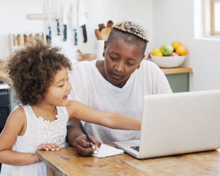 mom working from home in the kitchen with her daughter