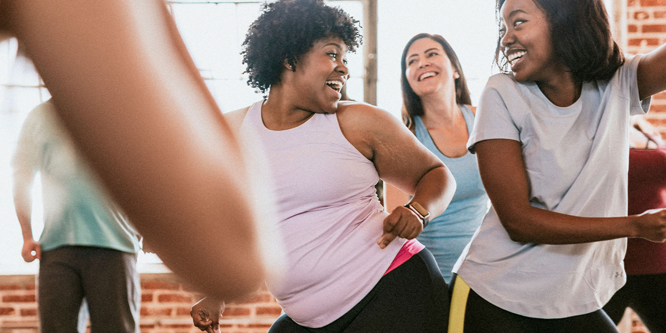 Two women laughing in dance cardio class - jazzercise in pregnancy