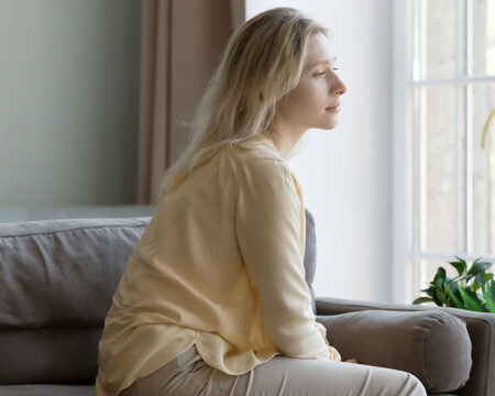 woman dealing with infertility looking out the window looking solemn Motherly