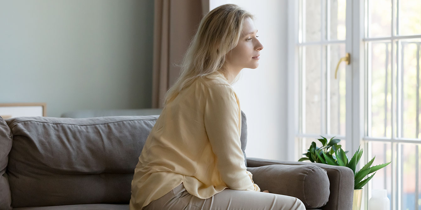 woman dealing with infertility looking out the window looking solemn