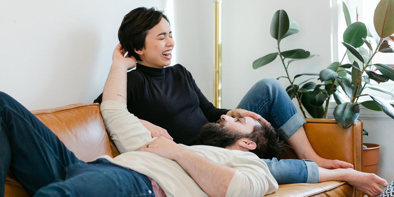 couple laughing on the couch together - how to connect with your spouse