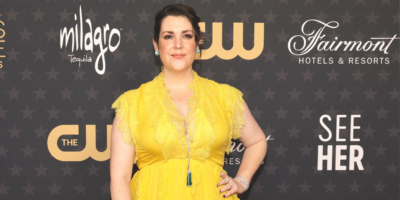 Melanie Lynskey posing in a yellow gown on the CW red carpet