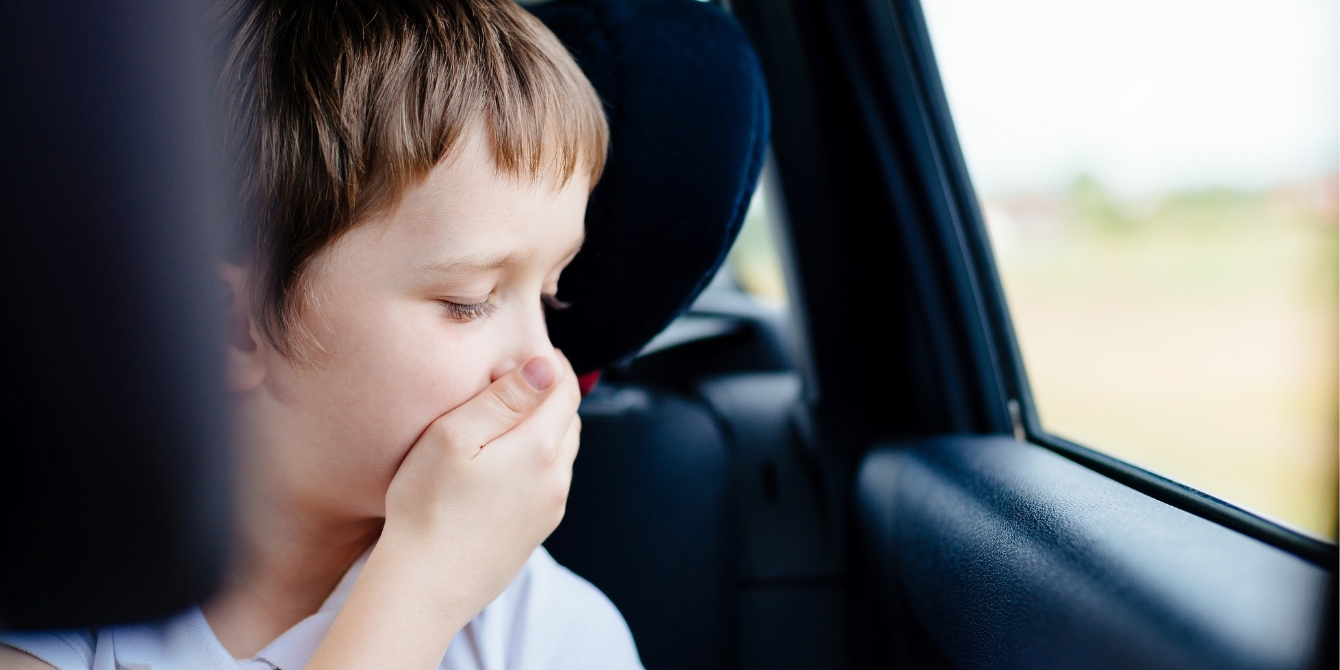 child holding hand over face in car to prevent motion sickness - motion sickness in kids