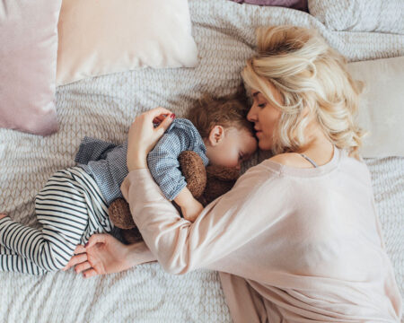 toddler and mom laying in bed cuddling Motherly