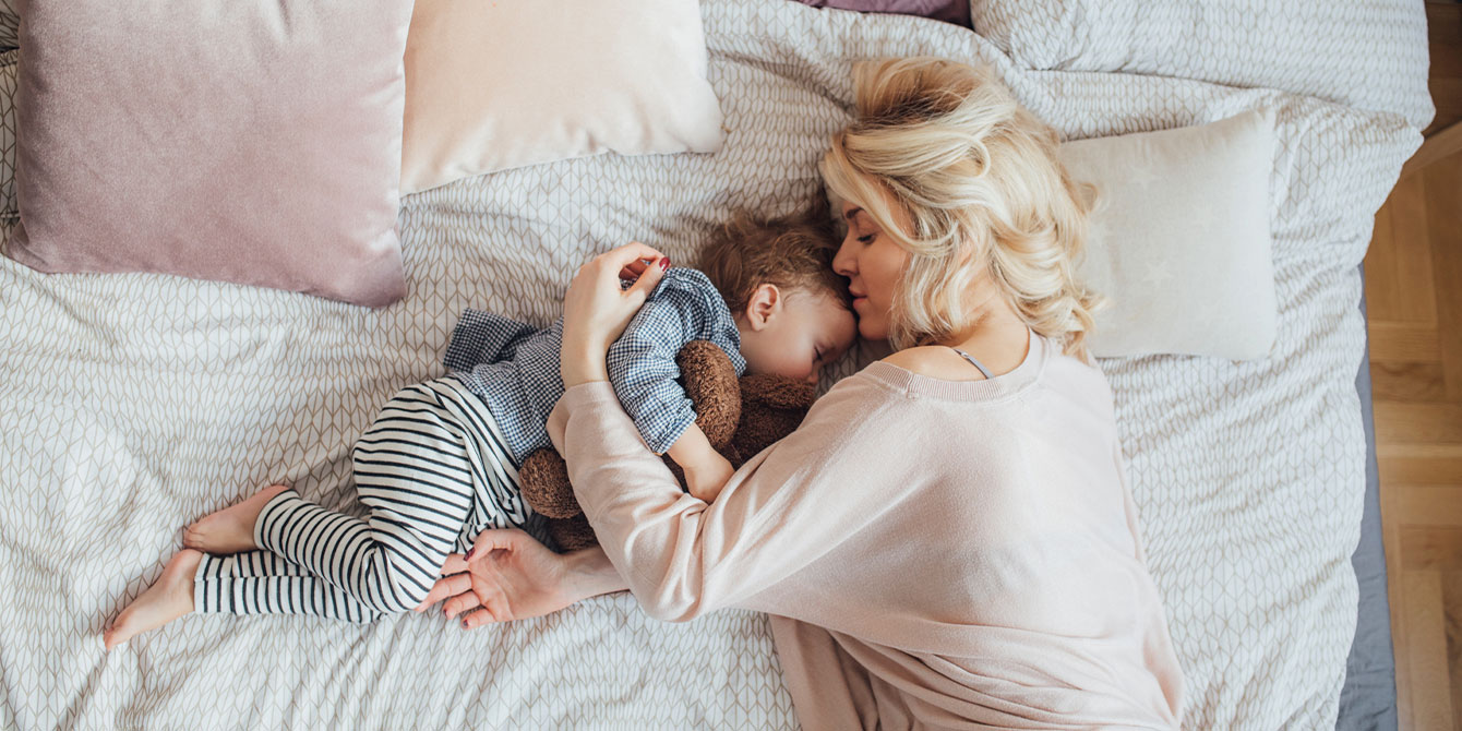 mom and child sleeping in bed together- getting your baby to sleep through the night