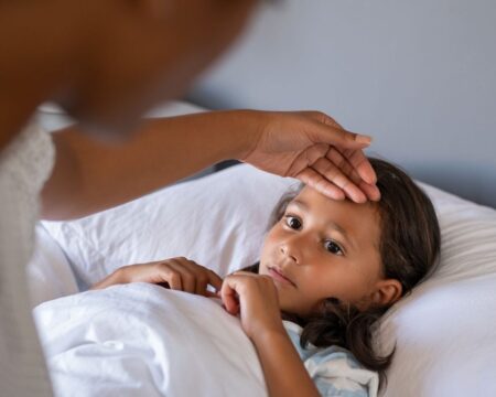 mom feels childs forehead for fever