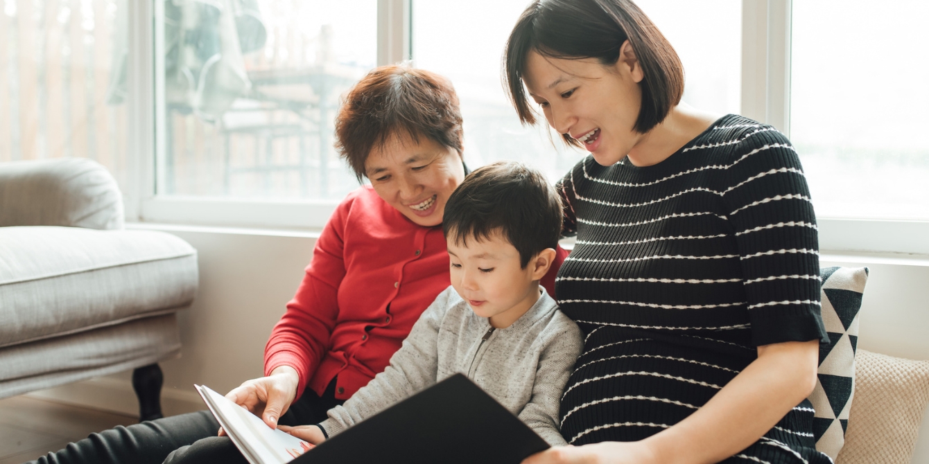 mom and grandma reading a book to her son