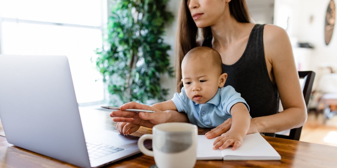 mom working with baby on her lap needing society to start advocating for working moms for equality