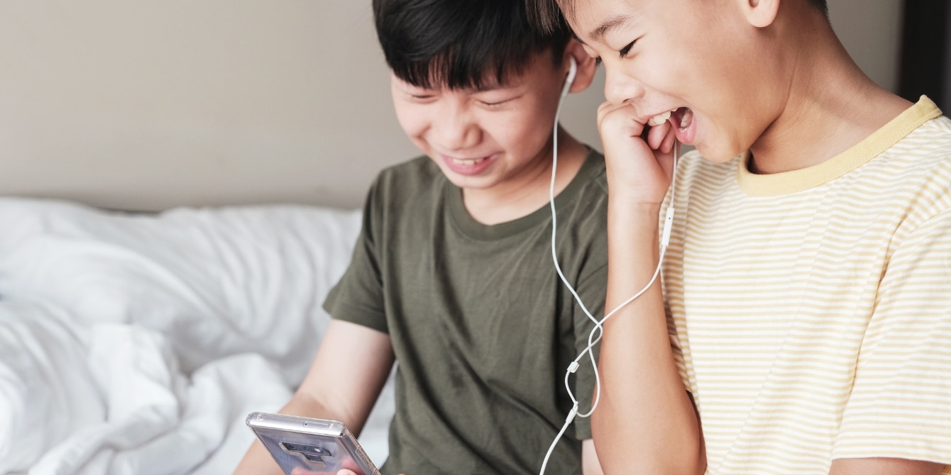 two young kids listening on headphones- podcasts for kids