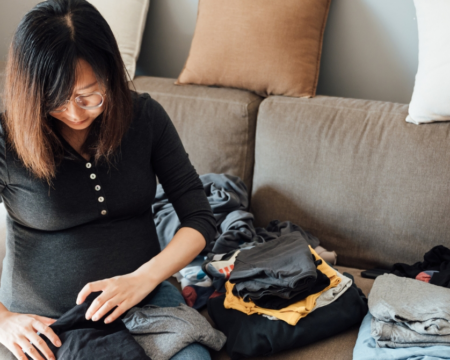 pregnant woman folding laundry on couch - gender equity at home