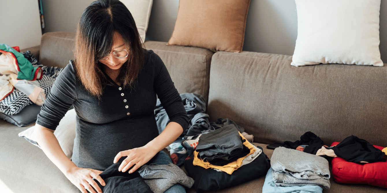 pregnant woman folding laundry on couch - gender equity at home