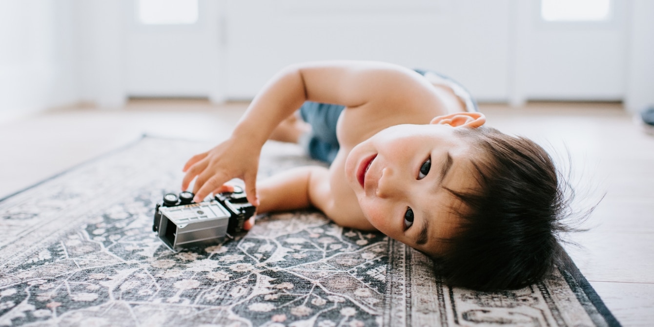 child playing with truck on the carpet - activities for 3-year-old