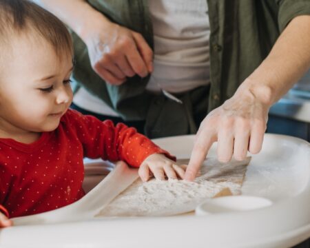 baby sitting in high chair sensory play flour Motherly