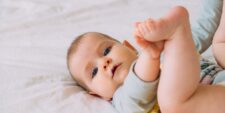 baby girl on bed holding her feet Motherly