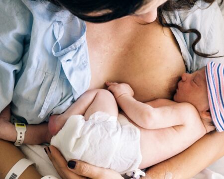 woman breastfeeding newborn baby in hospital Motherly