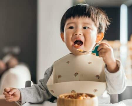 cute toddler asian boy wearing bib eating Motherly