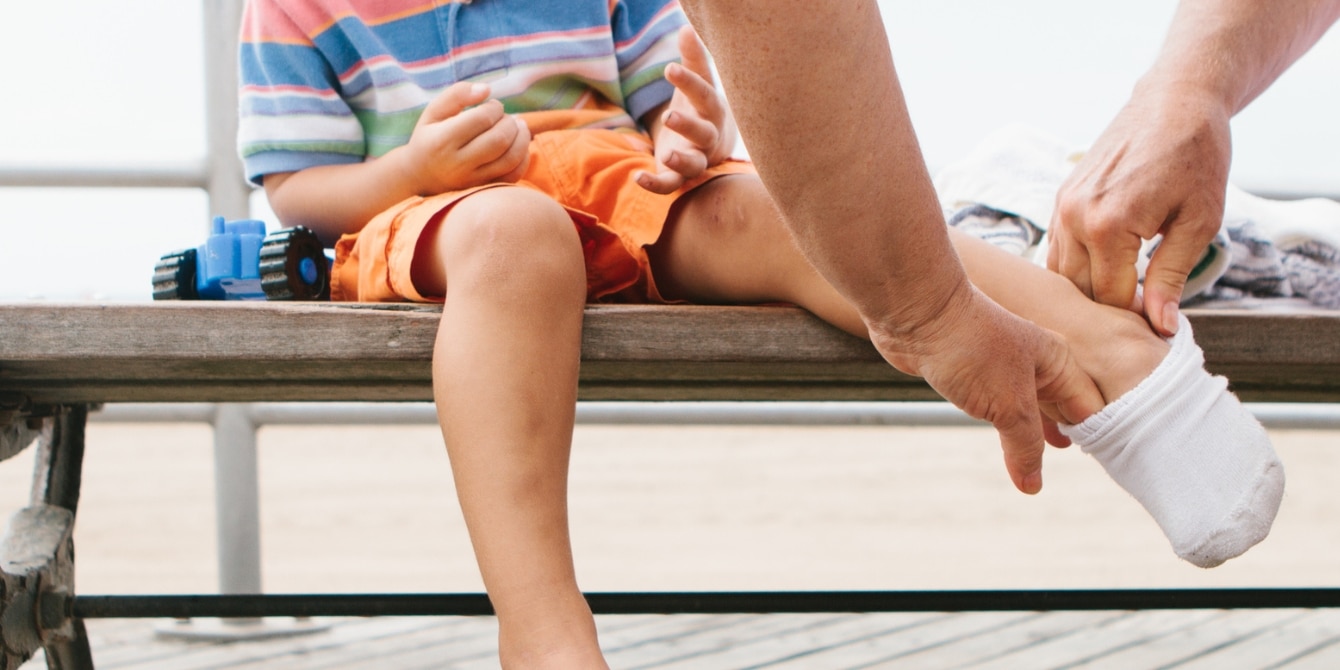 parent's hands putting socks on child's feet