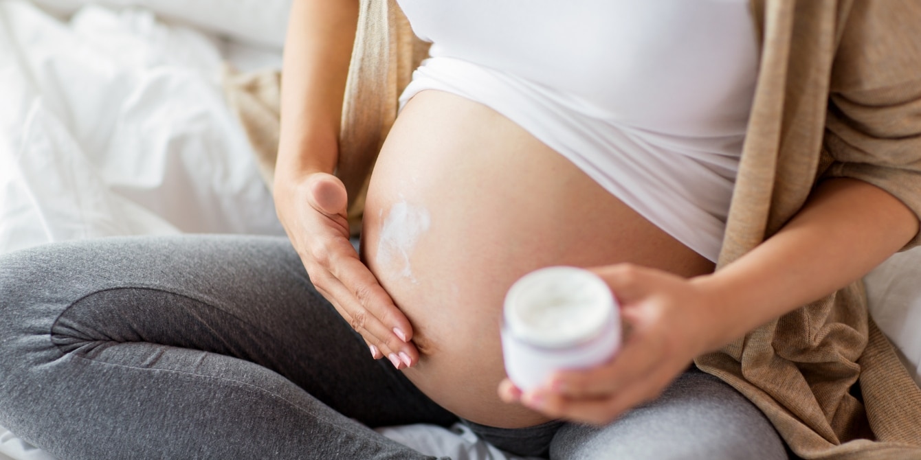 pregnant woman putting lotion on her belly - chemicals to avoid during pregnancy