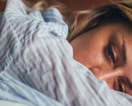 woman laying in bed sad infertility struggles Motherly