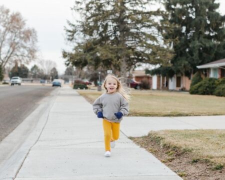 cute child running on neighborhood sidewalk