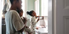 mom helping daughters brush teeth in bathroom Motherly