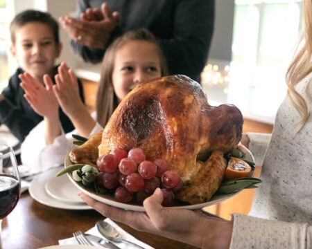 woman bringing thanksgiving turkey in to her family - thanksgiving hacks