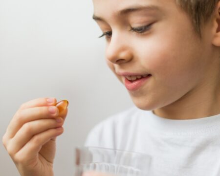 young boy holding pill