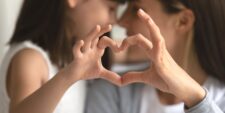 young girl and mom making heart with hands Motherly