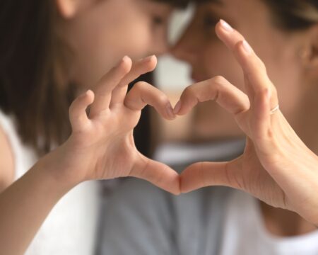 young girl and mom making heart with hands Motherly