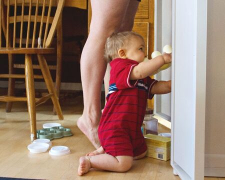 Toddler Playing In Cupboard By Mom