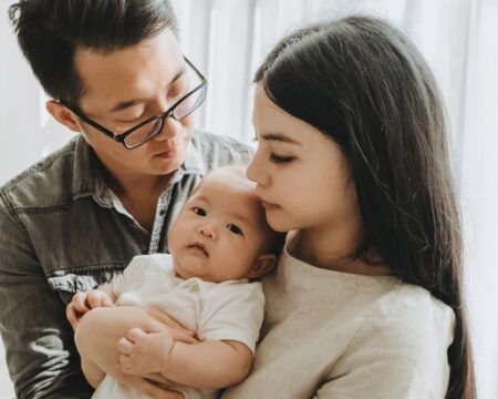 young couple holding their baby Motherly