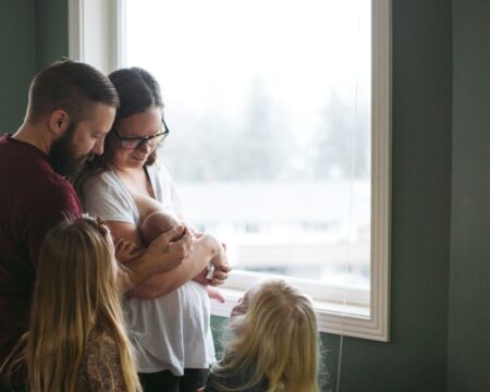 family gathered around mother feeding baby Motherly