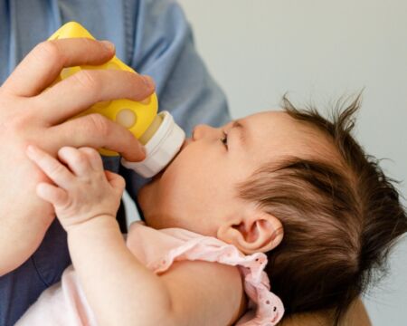 parent feeding baby with bottle Motherly