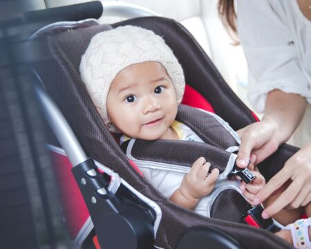 winter car safety mom securing baby in car seat Motherly