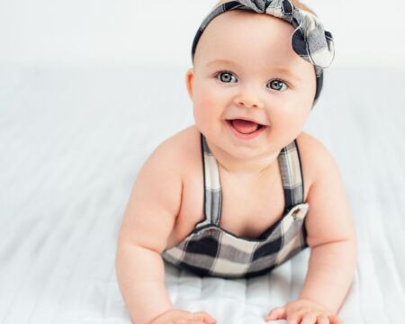 baby girl wearing bow smiling baby girl names Motherly