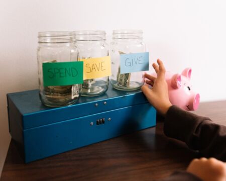child with money jars budgeting Motherly