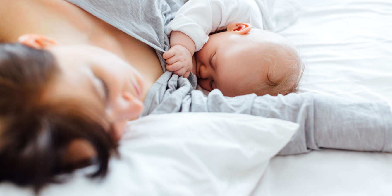 mom lying in bed nursing baby Motherly