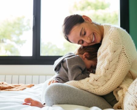 mother hugging toddler son on bed 1 Motherly