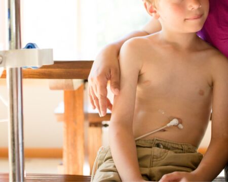 Boy being fed through g tube sitting with mother Motherly