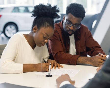 couple signing contract with car dealer buying safe family car