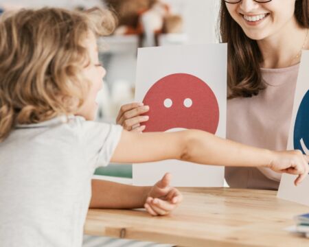 child pointing to happy face at therapist office Motherly