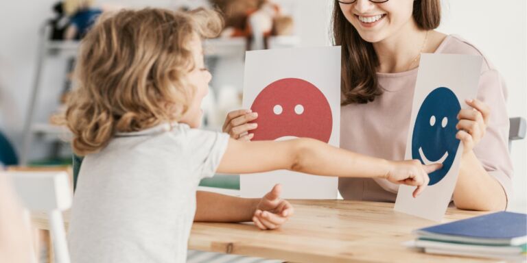 child pointing to happy face at therapist office Motherly