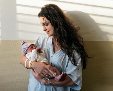 mom holding new baby in hospital Motherly