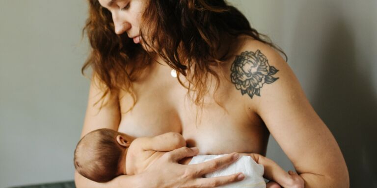 mother breastfeeding new baby Motherly