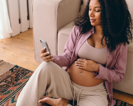 pregnant woman looking at her phone Motherly